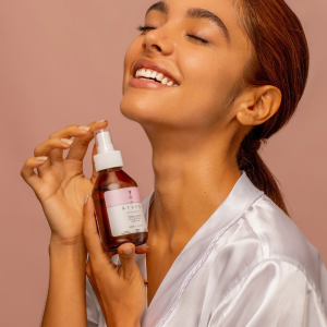 Mujer feliz con su Tónico facial de agua floral aruna que ayuda a disminuir los signos de fatiga